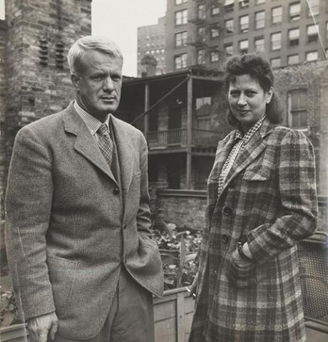 A photograph of a man and woman standing outside in coats. 