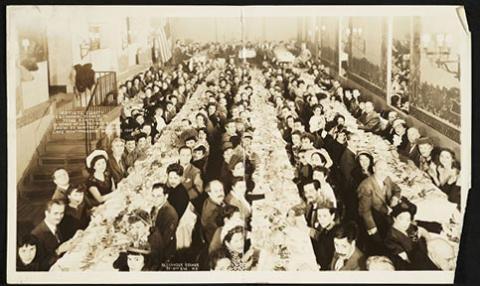A photo of three long tables with people eating on each side. 
