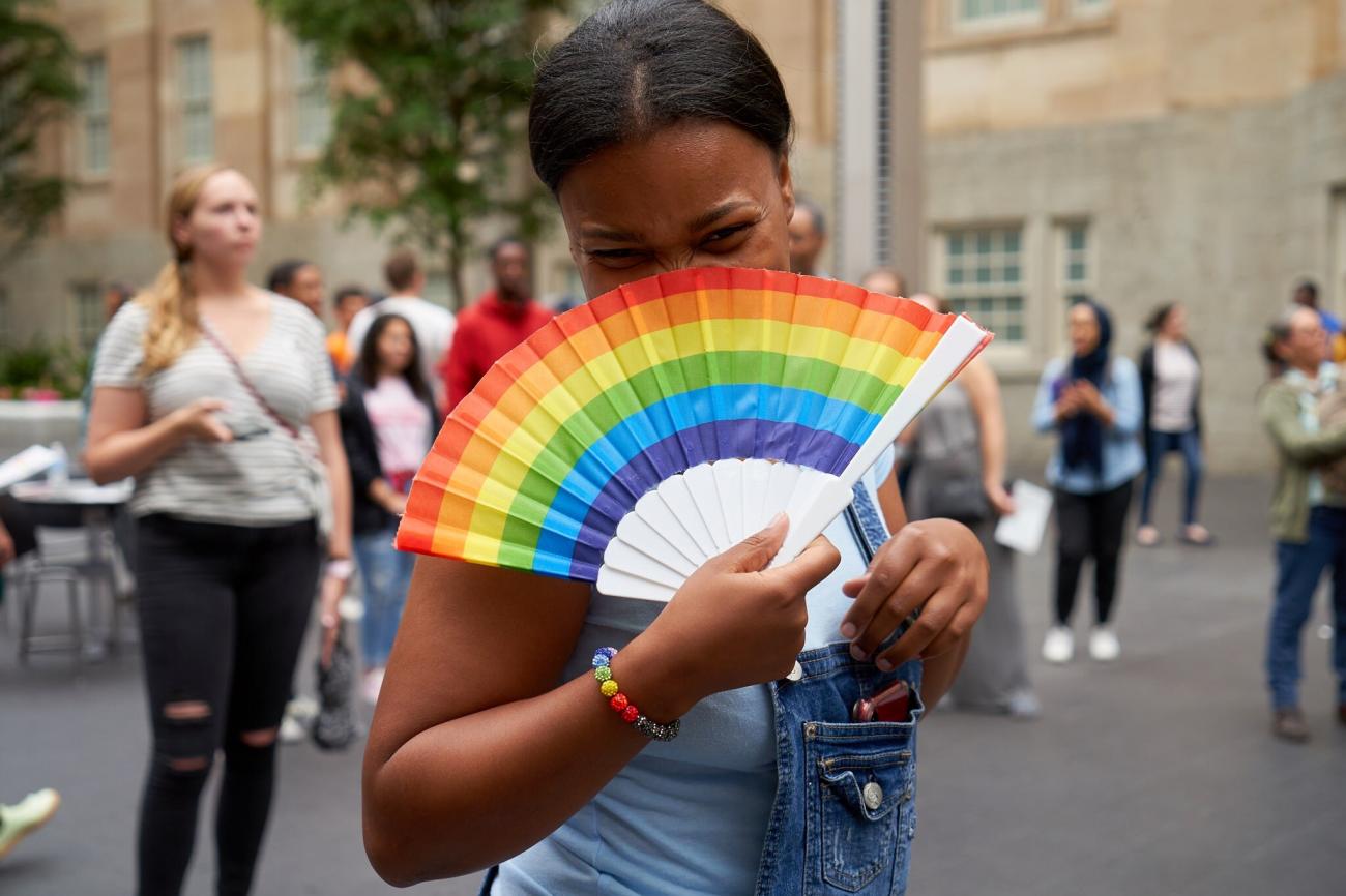 A photograph of a figure with a rainbow fan