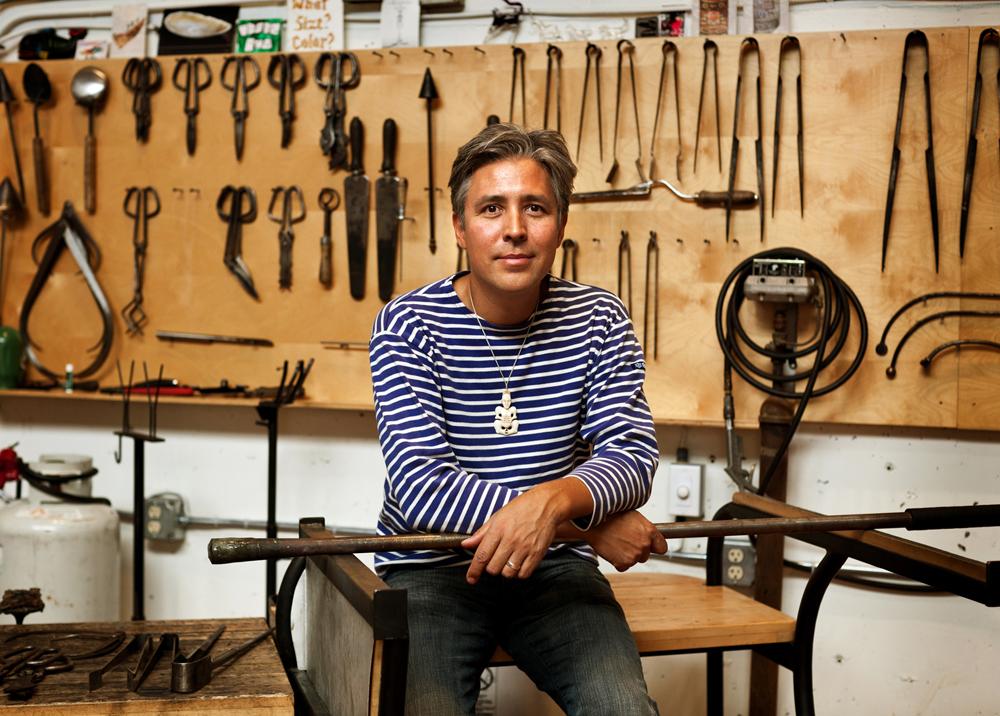 Artist sitting in front of a wall of tools