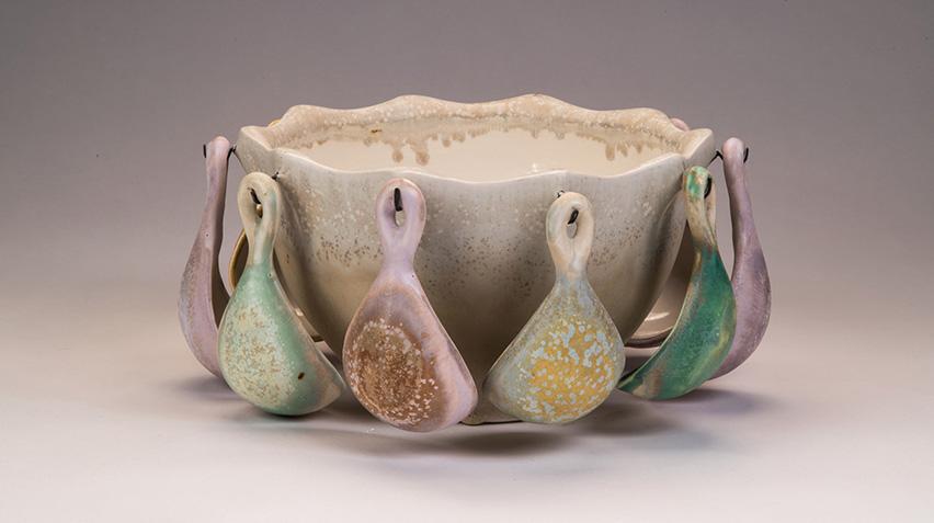 Ceramic bowl with ceramic spoons hanging all around its perimeter.
