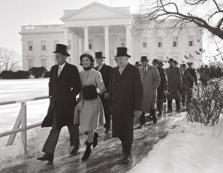 Procession of people following JFK and Jackie through a snowy scene