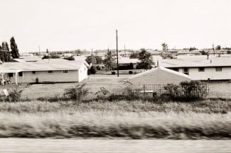 A photograph of a Illinois landscape with houses taken by automobile.