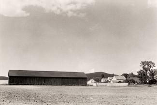 A photograph of a Massachusetts landscape with a building taken by automobile.