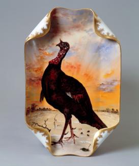 An image of Haviland & Company's porcelain dinner platter with a bird painted in the foreground and the sunset in the background. 