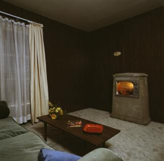 Interior of dark, wood-paneled living room with television facing a sofa