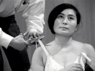 A photograph of a man cutting a womans bra strap.