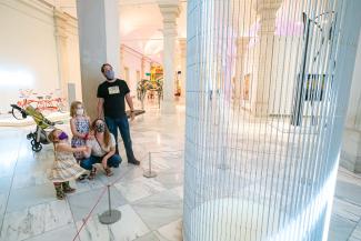 A man, woman, and two small children look upon an LED sculpture by Jenny Holzer