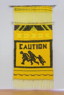 Yellow and black weaving with "Caution" printed on it with figures running 