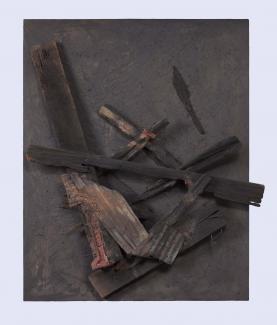 A square piece of dark brown wood is overlaid with wood pieces, metal, tin, and nails 