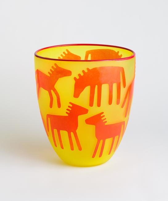 A yellow vase with stylized horses and deer in red