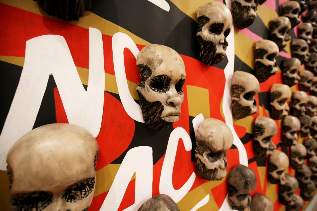 Blog - Invitational 2018, Dustin Farnsworth A detailed photograph of wood carved skulls on a wall.