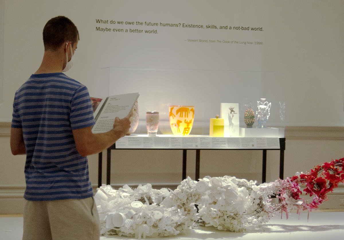 A visitor stands in the gallery, reading a binder of large print labels