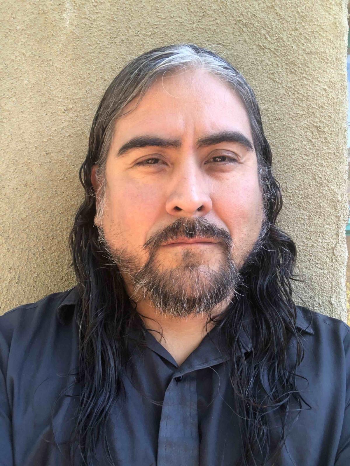 The artist Ravon Chacon stares directly into the camera in a black shirt