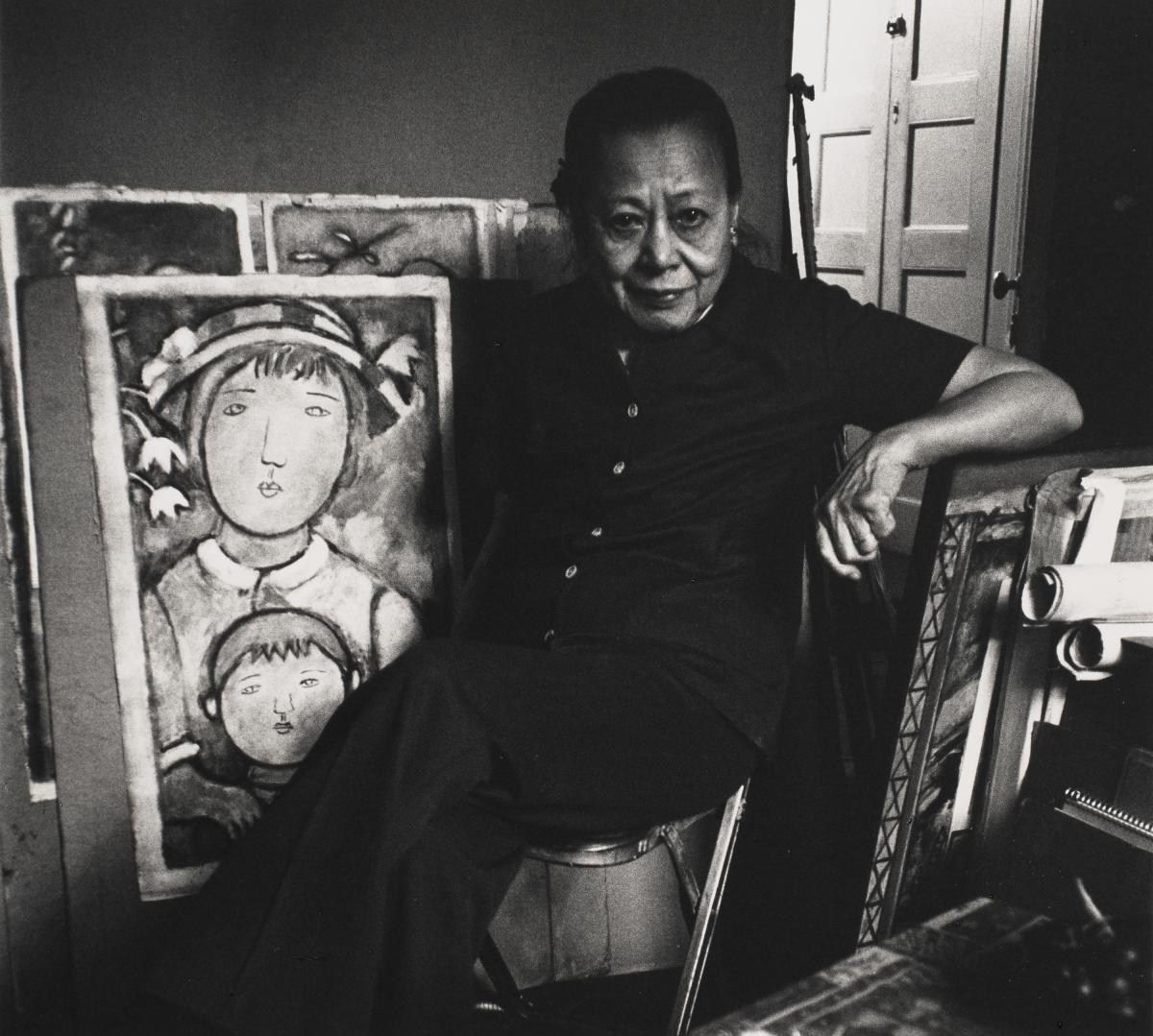 photo of a person sitting infront of artwork leaning on a wall