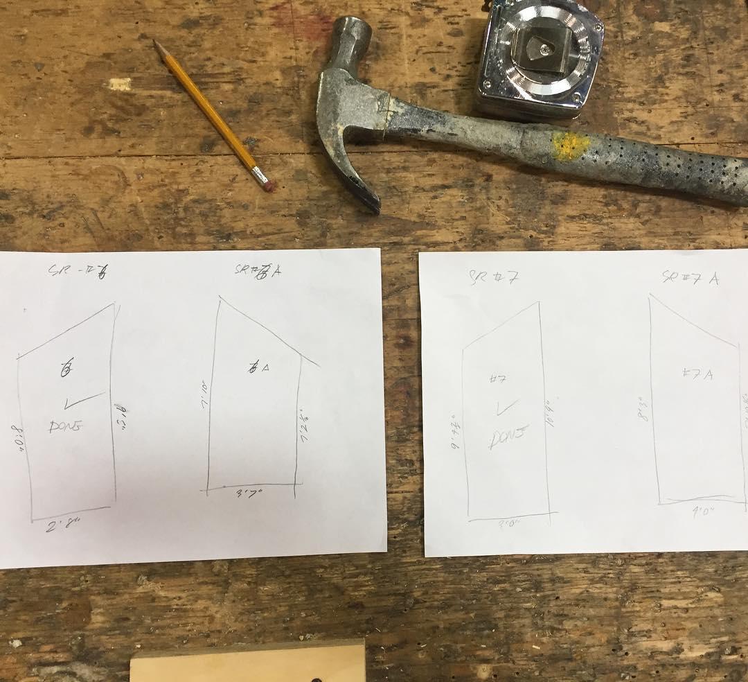 Photo of a table with paper drawings, a hammer, and other tools.