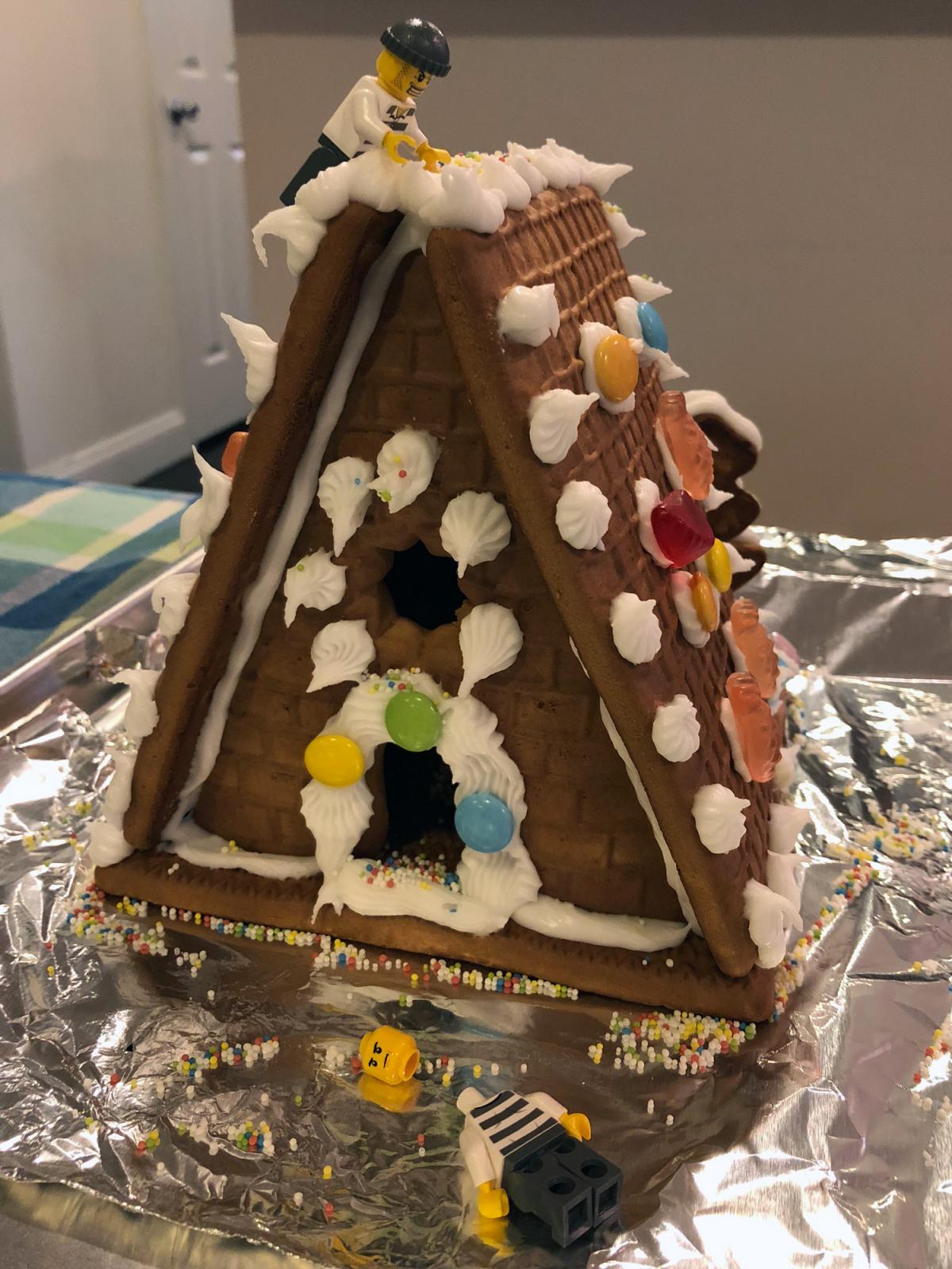 Gingerbread house with candy decorations and two LEGO figures.