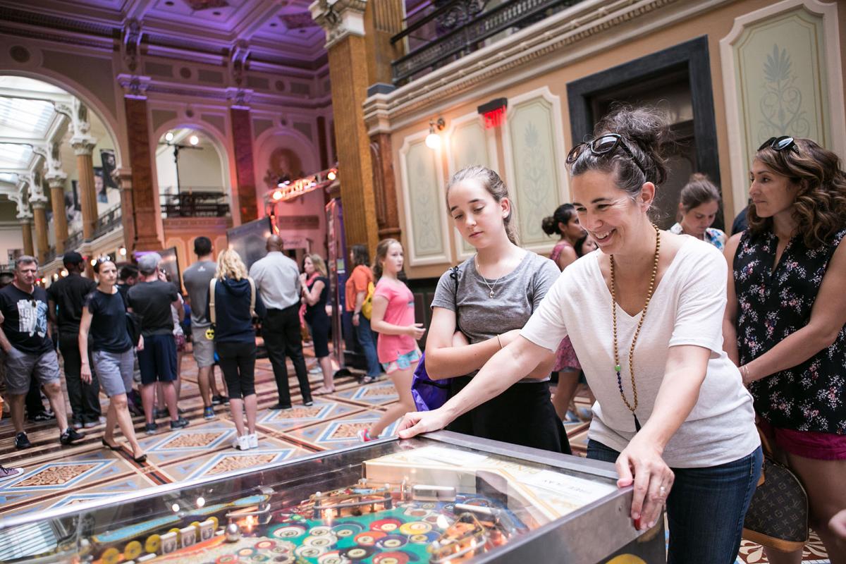 A photograph of a woman playing pinball inside the Smithsonian American Art Museum during SAAM Arcade.