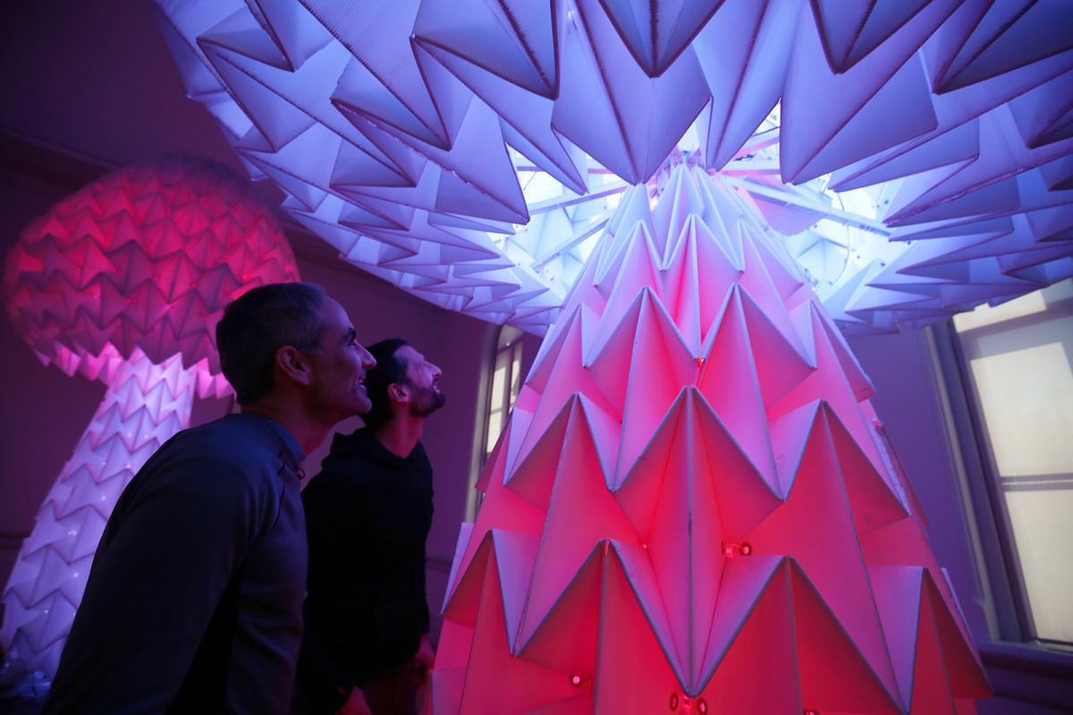 This is a photograph of two designers in Foldhaus looking up into Shrumen Lumen.