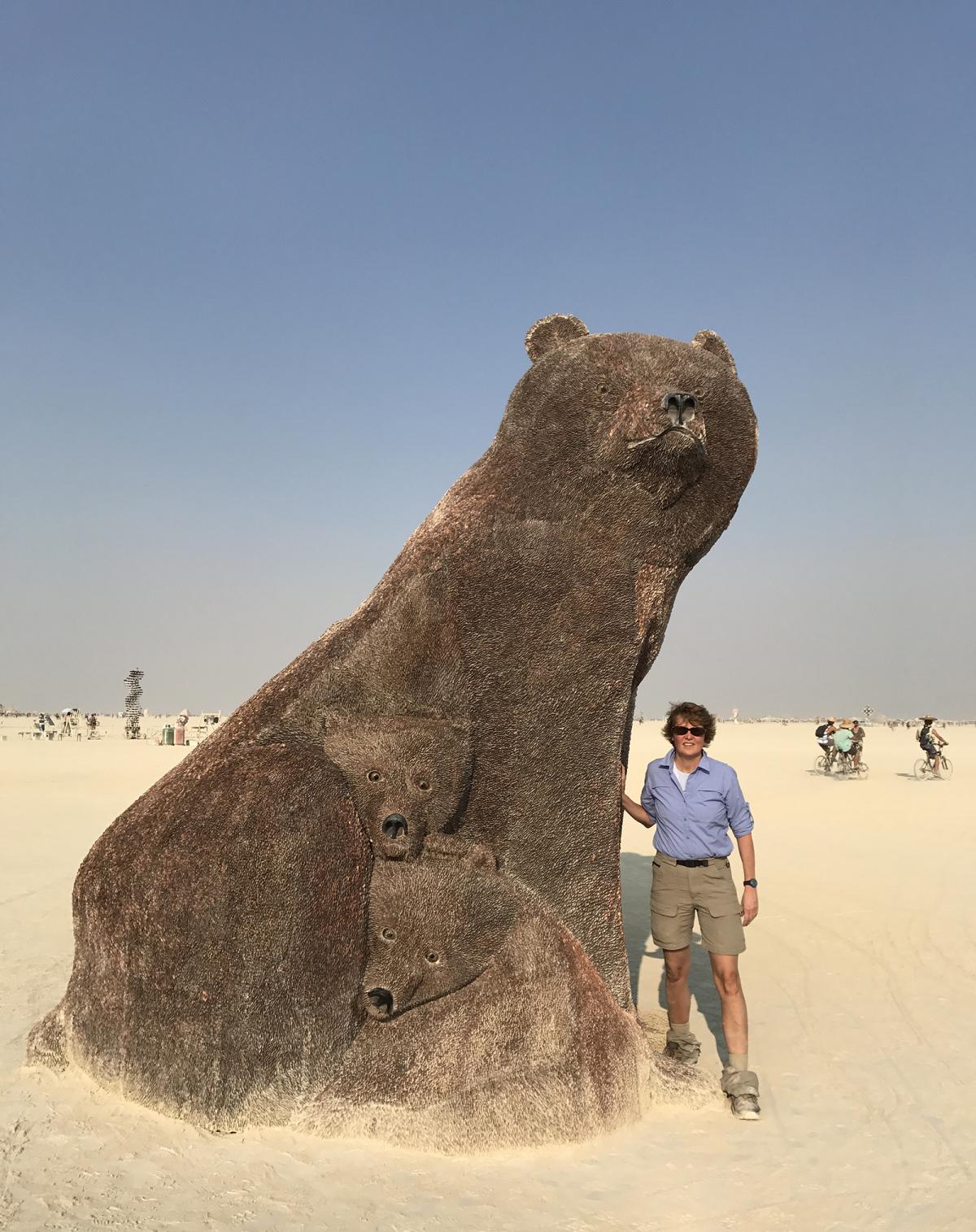 This is a photograph of Stephanie Stebich standing next to the Ferguson's Ursa Mater at Burning Man.