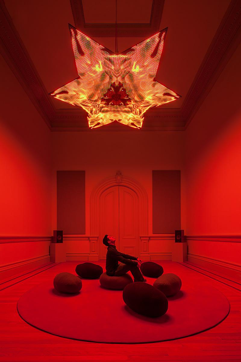 An image inside of a room with an LED star at the top and cushions for sitting at the bottom.