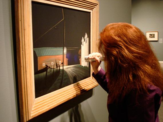 Paintings Conservator, Amber Kerr-Allison does a final inspection of George Ault's painting Bright Light at Russell's Corners with a UV flashlight just before the show opens.