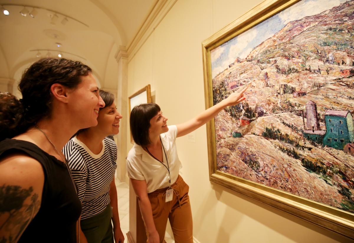 An image of three women looking at a piece of artwork.