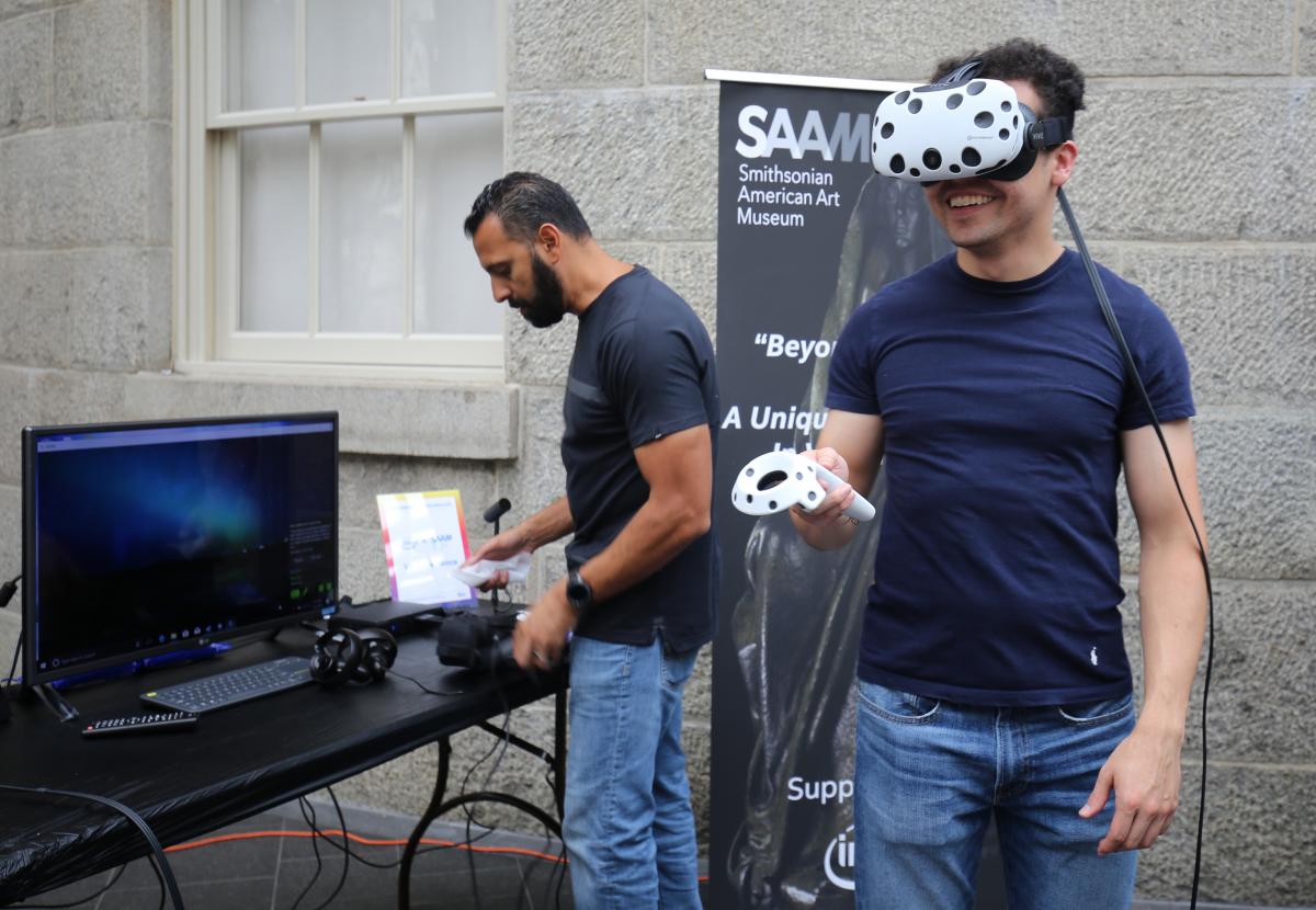 A photograph of a man with a VIVE headset on while playing a virtual reality game at the Smithsonian American Art Museum.