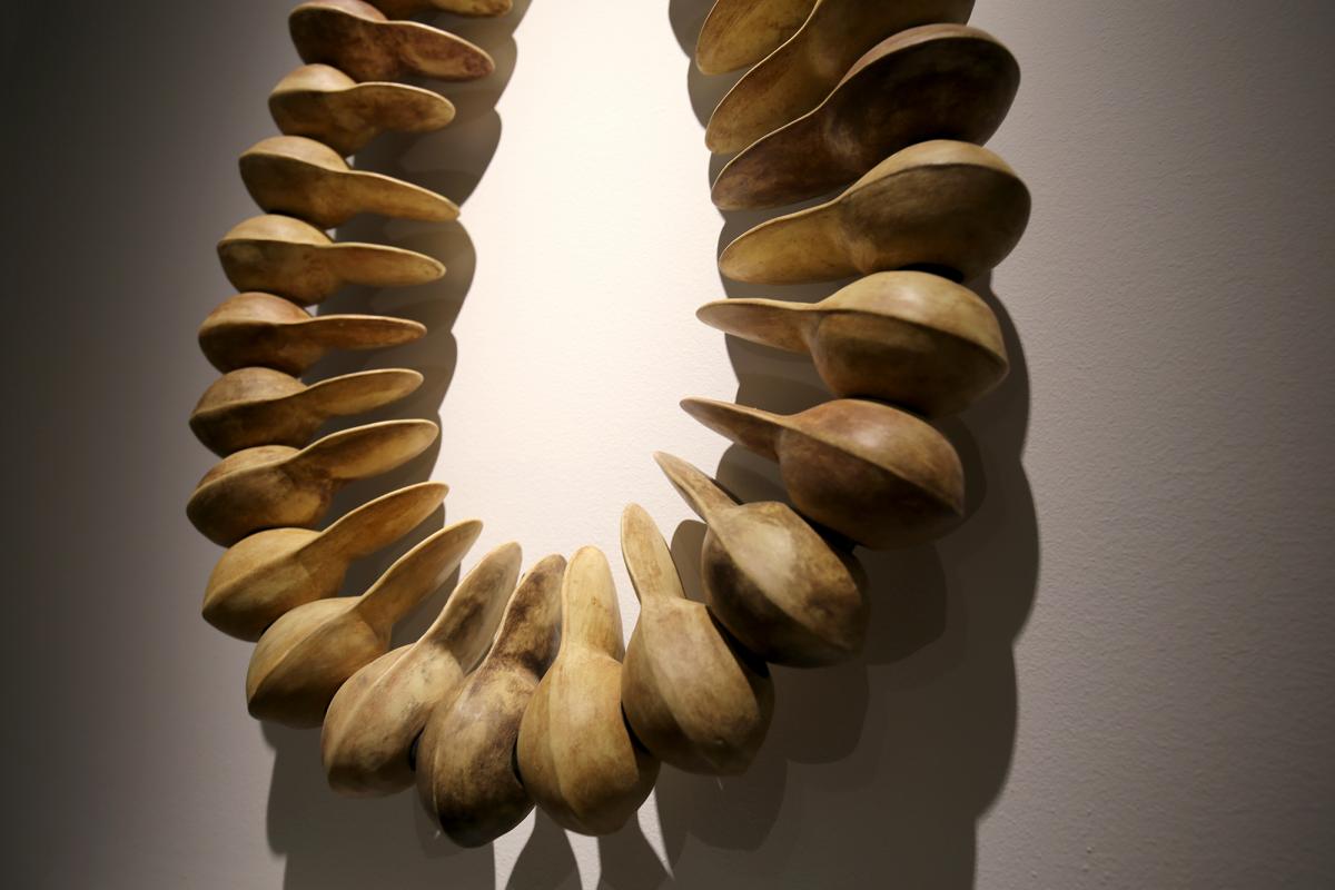 A photograph of the artwork, Ripened Banana, a large scale tan beads in the form of a necklace.
