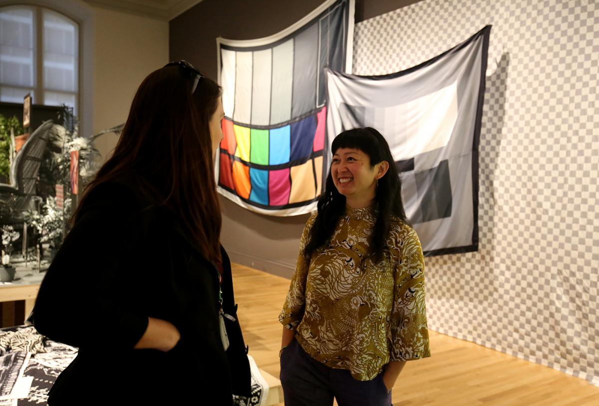 Two women talking to each other inside an art gallery.