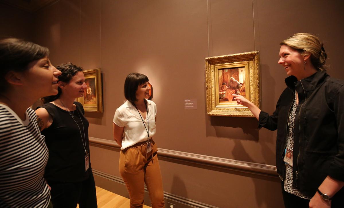 a photograph of four individuals looking at a work of art in a museum.