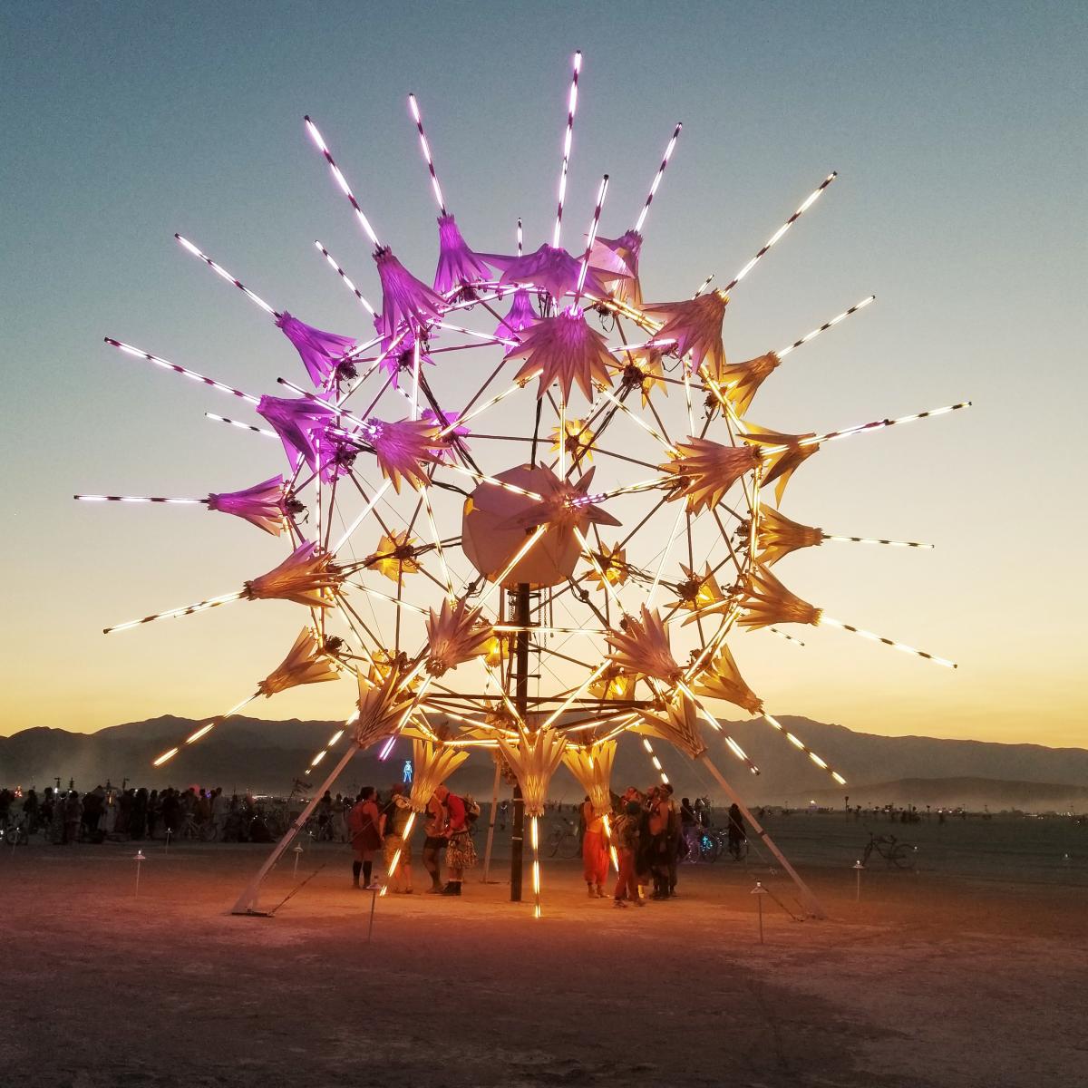 A photograph of a circular artwork with LED lights at night in the desert.