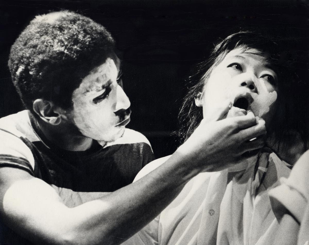 A photograph of a man holding a woman's mouth open.
