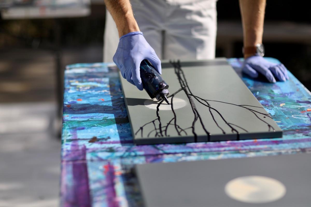 A detailed photograph of a hands on a table working on a painting.