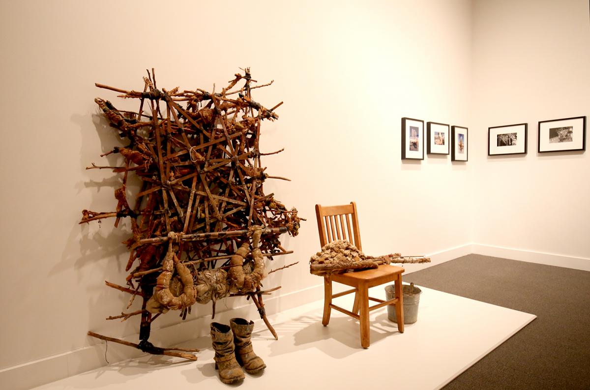 A photograph of artwork on a wall with a chair and combat boots. 
