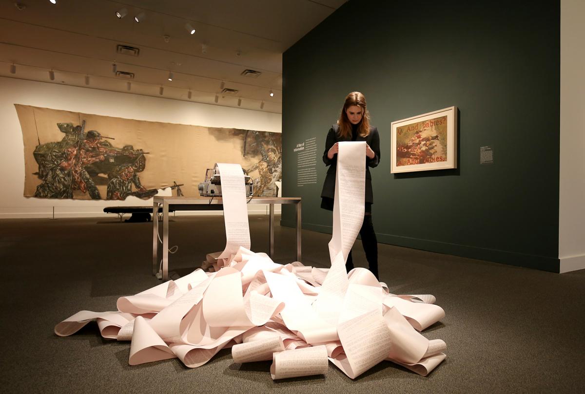 A woman looking at printed paper inside a gallery. 