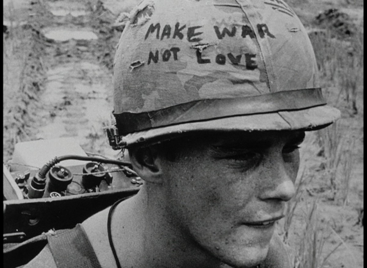 The face of soldier with a helmet that says "make war not love"
