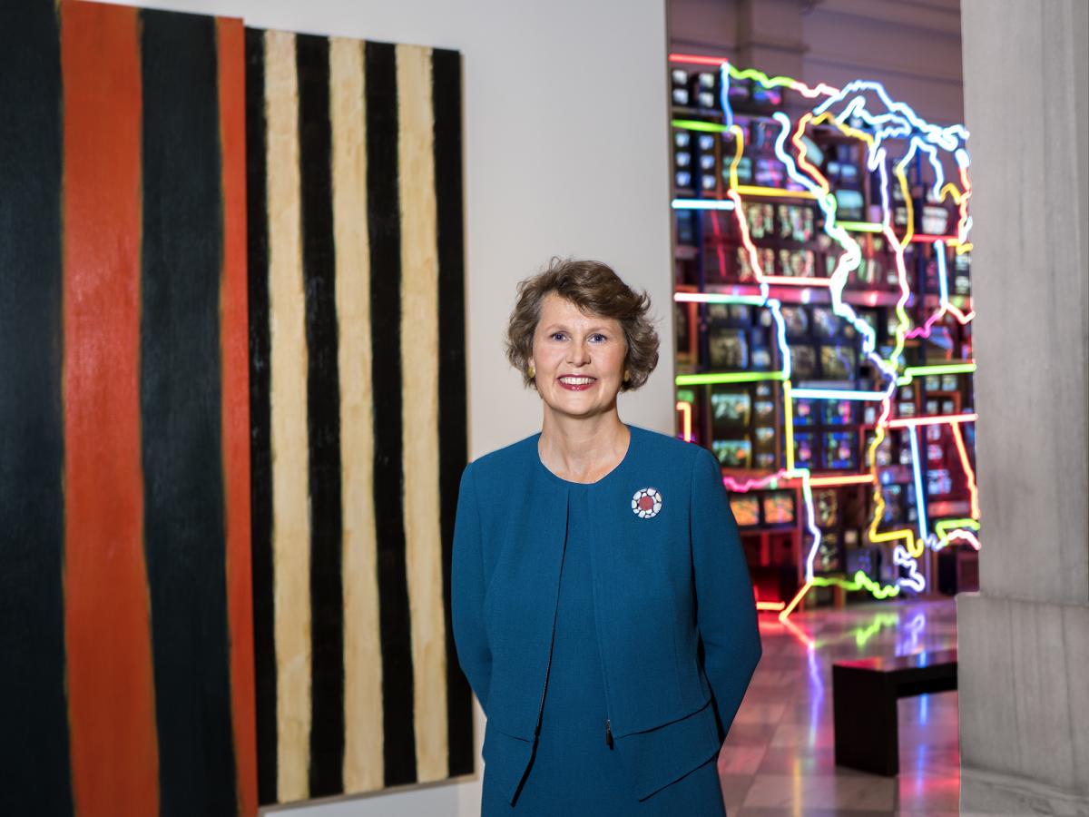 A photograph of a woman standing in front of artwork inside a museum.