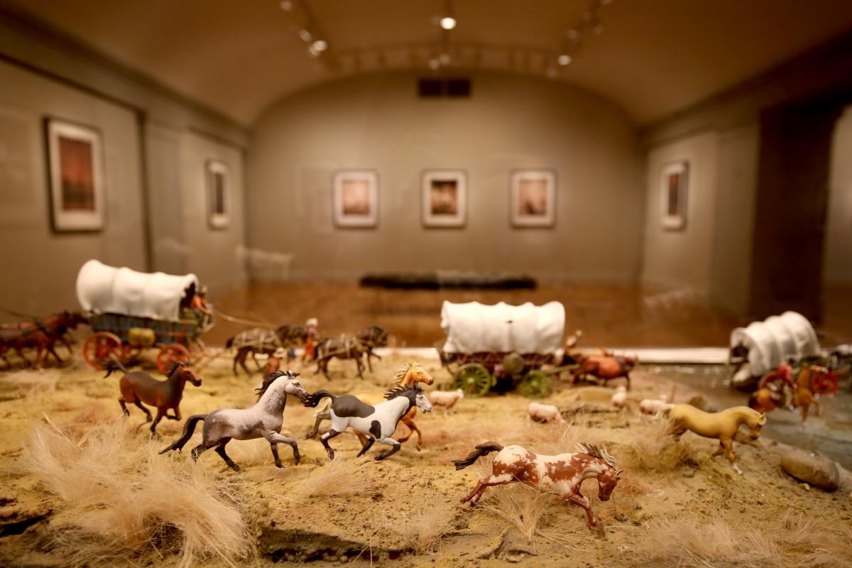 A photograph of an installation of toy figurines in a wild west landscape. 