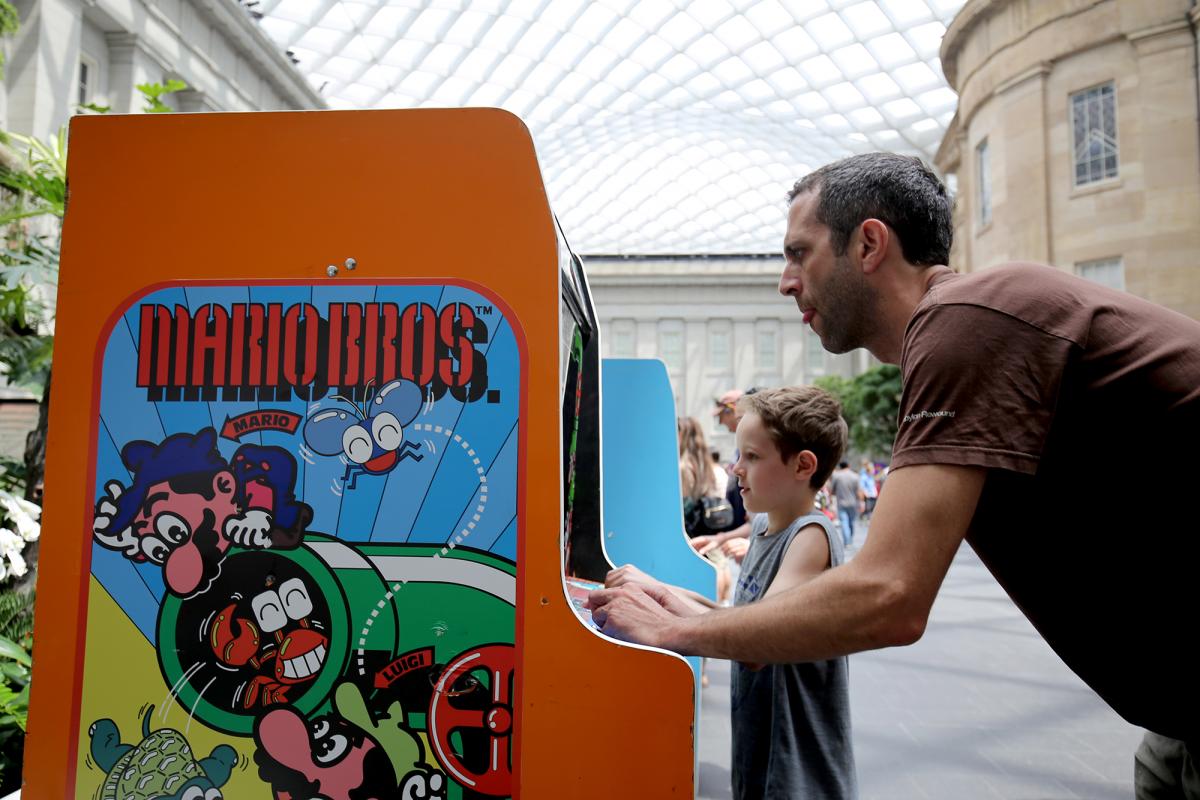 A photograph of a man playing a video game with his son.