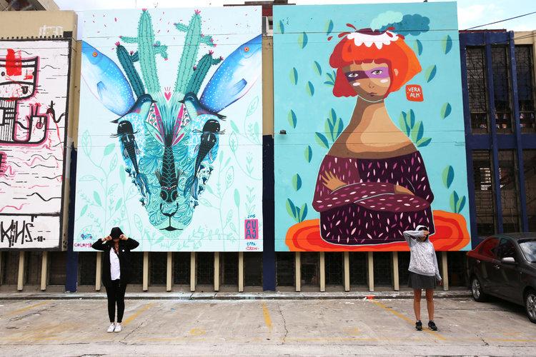 People stand in front of murals created by street artists