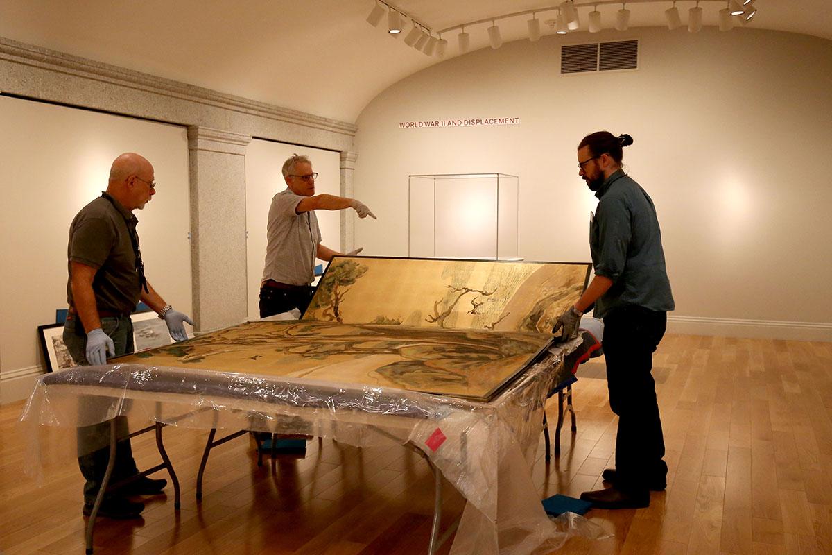 Three men unpacking a silk screen.