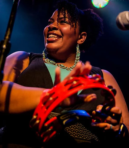 Picture of a woman playing the tambourine. 