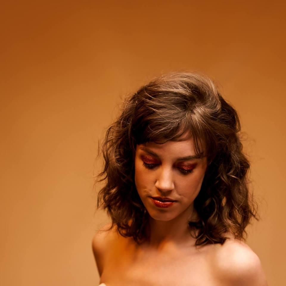 Picture of a woman with dark brown hair against a gold background.