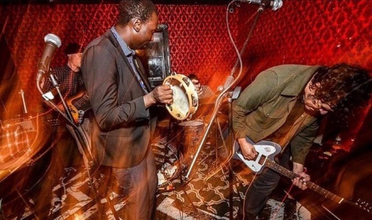 Two people in a band playing the guitar and the tambourine.