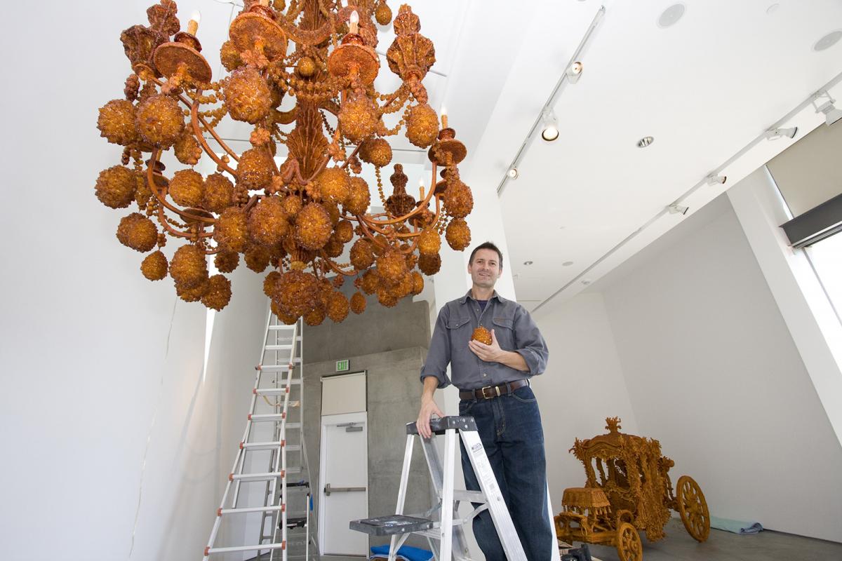 A photograph of an artist installing and artwork in a gallery. 