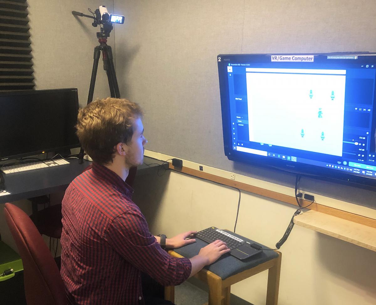 Student playing video game with camera recording session on the upper left.