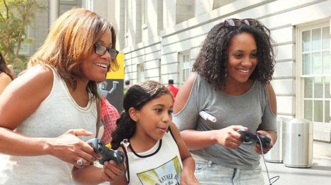 A photograph of three women playing video games