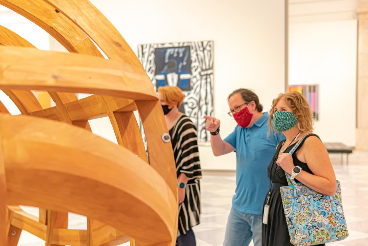 A photograph of individuals inside an art museum with masks on. 