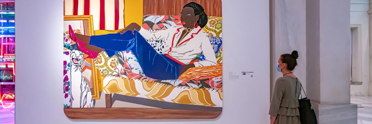 A photograph of a person in an art gallery with a mask on.